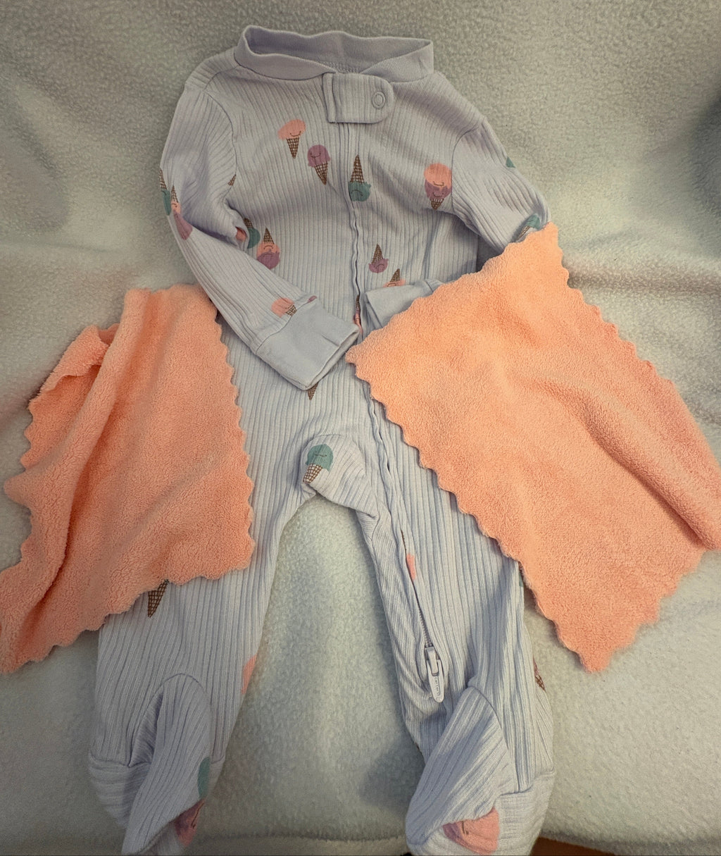 Light purple zip up bodysuit and two pink washcloths 