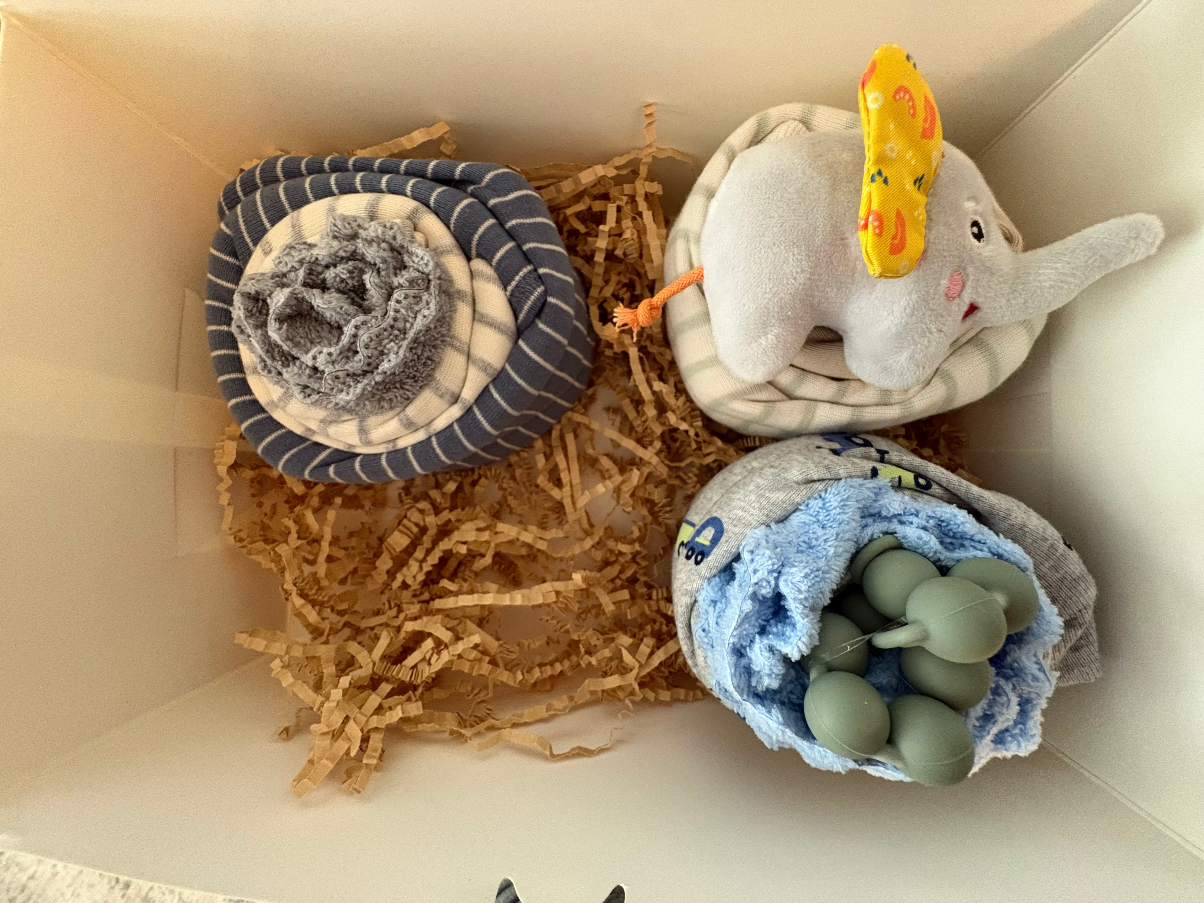 Third cupcake in box is a gray truck onesie with blue wash cloth and green pacifier rope